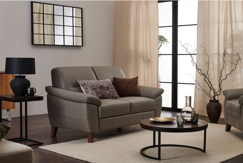 Grey leather sofa with black mirror and industrial-style furniture.