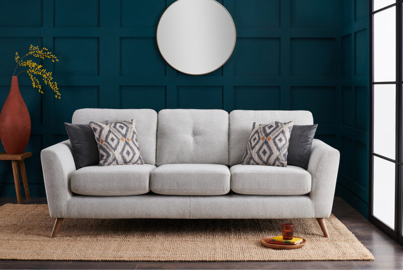 Living room with dark blue panelled wall featuring the grey Bridgeport sofa with patterned scatter cushions.