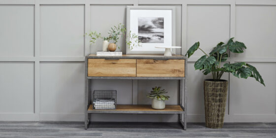 Brooklyn industrial-style console table with art and houseplants against a grey panelled wall.