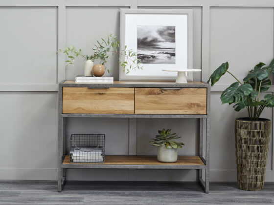 Brooklyn industrial-style console table with art and houseplants against a grey panelled wall.