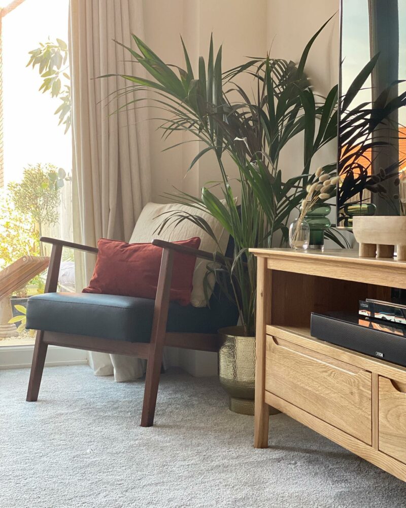 Copenhagen natural oak TV unit placed next to a chair and house plant.