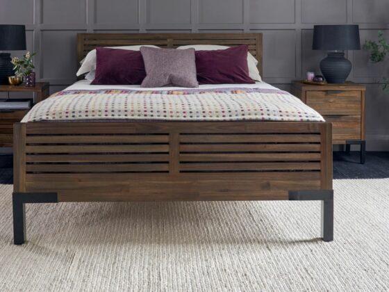 Dark stained oak and metal bed with matching bedside tables with black table lamps.