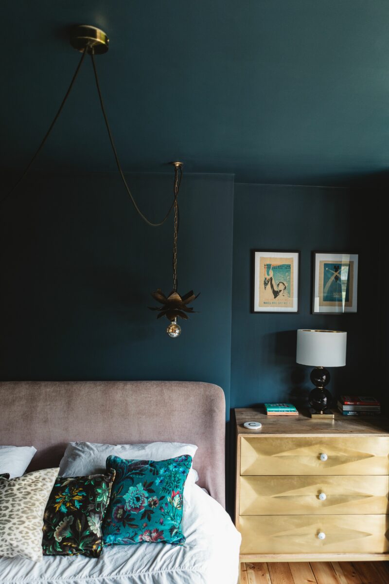 Dark moody blue bedroom styled by Maxine Brady with statment cushion, gilded furniture and accessories.