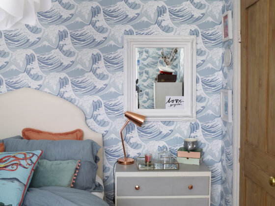 Bedroom styled by Maxine Brady featured wave-patterned wallpaper and an upholstered bed with coral and blue cushions.