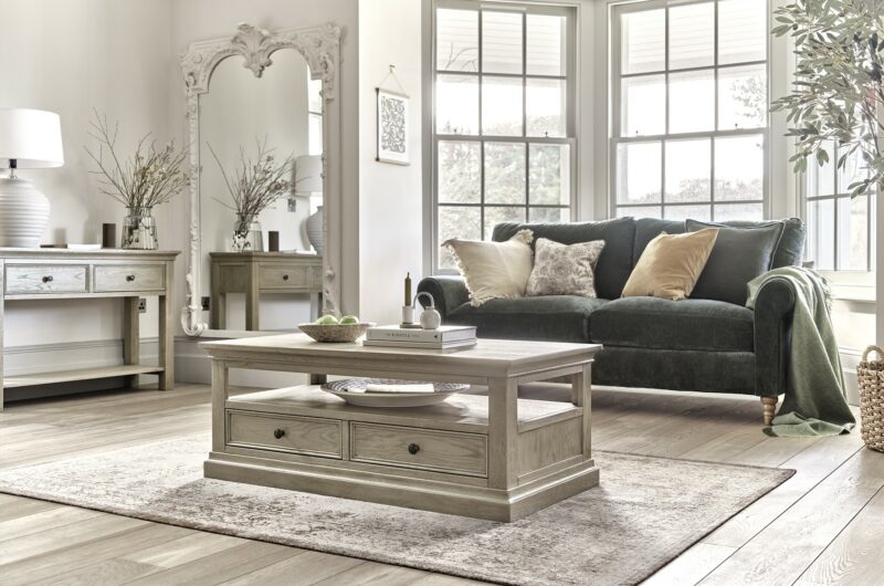 Oak Furnitureland Burleigh weathered oak coffee table, console table and dark green Bramble sofa in a light-filled living room.