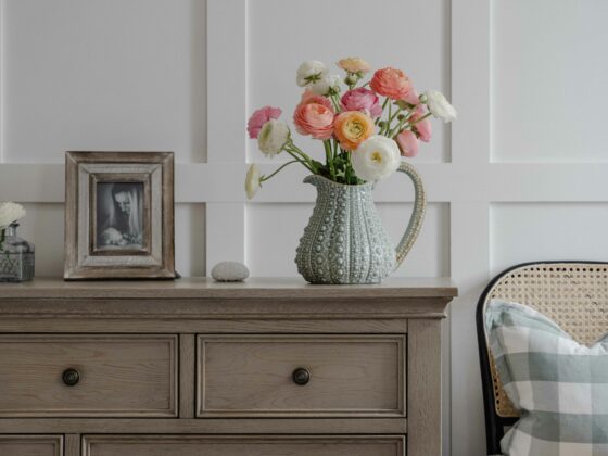 Burleigh weathered oak chest with a bright bunch of flowers in a vintage jug and other decorative accessories.