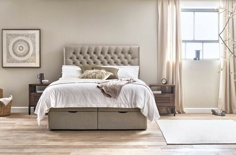 Elegant warm grey bedroom with a mink-coloured upholstered bed with textured cushions.