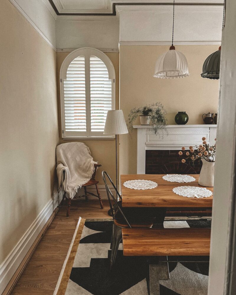 Industrial-style oak and metal dining table and bench seating, in a period living room with cream walls and a feature fireplace.