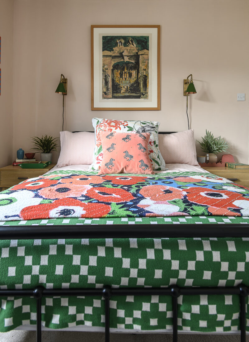 Wrought iron bed with colourful bedding and thrown with bedside tables on either side.