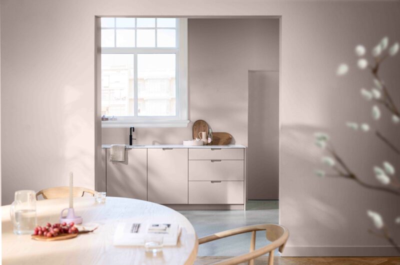 Dining room leading into a kitchen with the walls painted in Dulux Colour of the Year 2024 Sweet Embrace, a delicate pale pink.