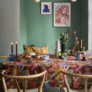 A dining table with chairs-dining room furniture-patterned table cloth-wooden wishbone chairs-statement lighting-green alcove