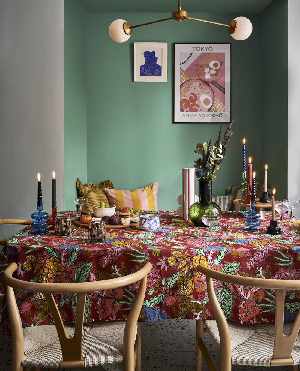 A dining table with chairs-dining room furniture-patterned table cloth-wooden wishbone chairs-statement lighting-green alcove