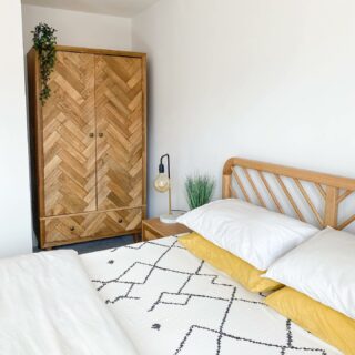 A bed, beside table and wardrobe-bedroom furniture-monochrome and yellow bedding-wooden bedside table-wooden triple wardrobe-wooden bed-bulb lamp