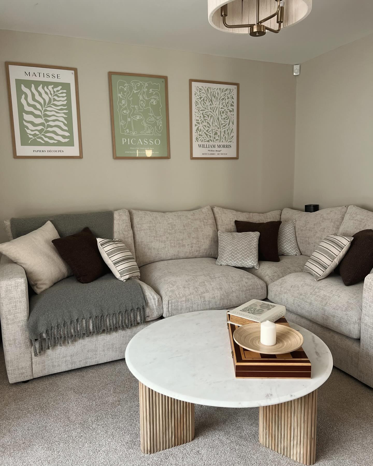 A modular corner sofa-living room furniture-beige corner sofa-monochrome accent cushions-marble and fluted wood coffee table-neutral walls-grey throw-green and white statement wall art
