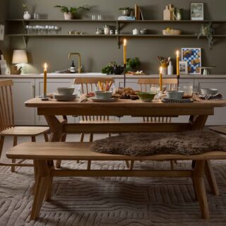 A dining table, display cabinet and bench-kitchen diner furniture-oak dining table set-neutral textured rug-spindle back chairs-olive green walls-sheepskin rug-tapered candles-soup bowls-bistro curtain-grey kitchen-open kitchen shelving-brass tap-autumnal tablescape