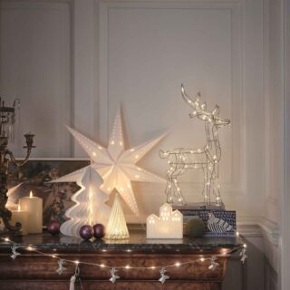 A sideboard-living room furniture-dark wooden sideboard-fairy lights-white star light-wire reindeer light-paper Christmas tree decorations-cream pillar candles-candelabra-painting-purple baubles-white panelled walls