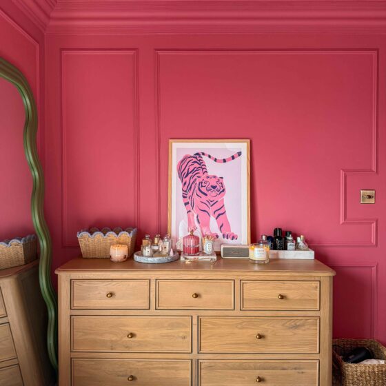 A chest of drawers-bedroom furniture-bright pink walls with panelling-oak chest of drawers-green wiggle floor standing mirror-parquet flooring-tiger wall art-scallop edge storage basket-marble trays-perfume-candles-skincare