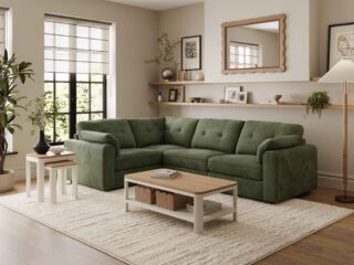 A corner sofa, coffee table, and nest of tables-living room furniture-dark green corner modular sofa-wooden and cream painted coffee table with shelf-wooden and cream painted nest of tables-cream textured rug-dark wooden floor-scallop edged mirror-built in wooden sheving-floor standing lamp-framed wall art-potted house plant-crittall windows-sheer blind