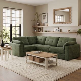 A corner sofa, coffee table, and nest of tables-living room furniture-dark green corner modular sofa-wooden and cream painted coffee table with shelf-wooden and cream painted nest of tables-cream textured rug-dark wooden floor-scallop edged mirror-built in wooden sheving-floor standing lamp-framed wall art-potted house plant-crittall windows-sheer blind