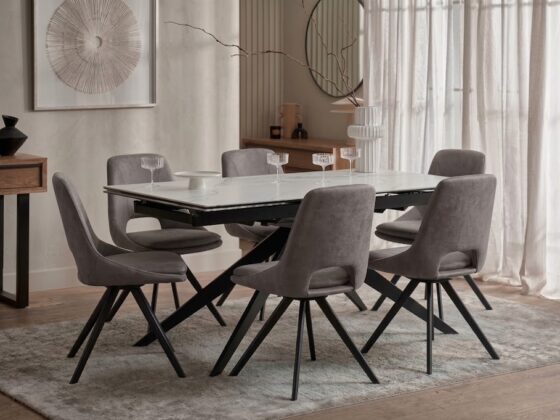A dining table and chairs-dining room furniture-ceramic table-grey upholstered dining chairs-dark wood cabinetry-neutral rug-warm neutral walls-abstract artwork