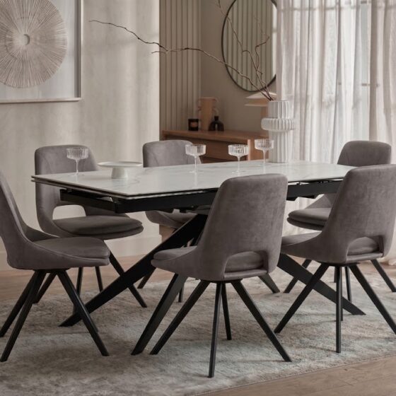 A dining table and chairs-dining room furniture-ceramic table-grey upholstered dining chairs-dark wood cabinetry-neutral rug-warm neutral walls-abstract artwork
