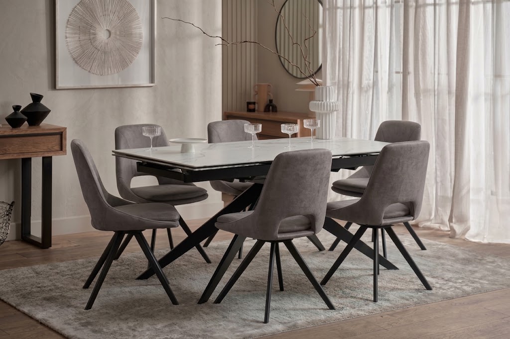 A dining table and chairs-dining room furniture-ceramic table-grey upholstered dining chairs-dark wood cabinetry-neutral rug-warm neutral walls-abstract artwork